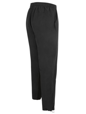 A pair of black pants is presented from a side angle. The pants have an elastic waistband and appear to have pockets on the sides and rear. The pant legs are straight and finished with drawstrings at the ankles.