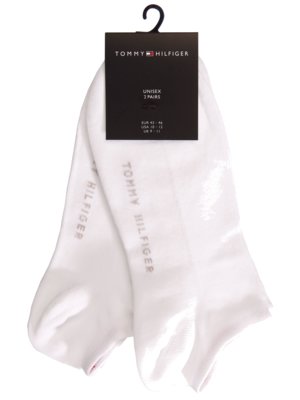 Ein Paar weiße Socken mit dem Markennamen Tommy Hilfiger, die an einem schwarzen Anhänger befestigt sind. Der Anhänger zeigt das Logo und Informationen wie "Unisex" und Größenangaben. Die Socken sind in der Verpackung gefaltet.