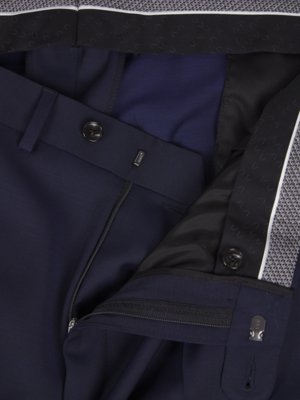 Close-up view of navy blue suit trousers. The zipper is partially open and the waistband has buttons and a hook closure. A portion of the inner lining is visible. There is a patterned band at the waist.