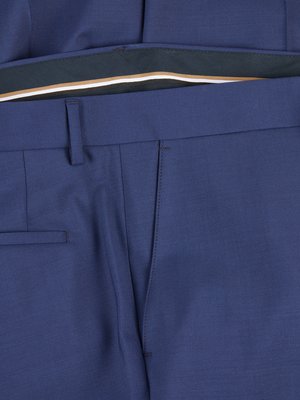 Close up of a blue suit pants. The top of the pants is visible, including a belt loop, a pocket, and a seam running down the leg. Inside the pants, a visible waistband.
