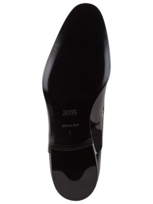 Nahaufnahme von der Unterseite eines schwarzen Herrenschuhs. Auf der Sohle sind das BOSS-Logo, "MADE IN ITALY" und eine Schuhgröße zu sehen. Der Schuh hat eine glänzende Oberfläche.