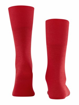 Zwei rote Socken auf weißem Hintergrund. Die Socken sind aus weichem Stoff und haben oben einen gerippten Bund. Die linke Socke ist flach, die rechte zeigt die Form eines Fußes.
