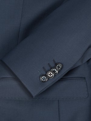 Nahaufnahme eines blauen Anzugs. Der Ärmel ist im Bild zu sehen, vier Knöpfe sind auf der Manschette zu sehen. Der Stoff des Anzugs ist glatt und strukturiert. Der Hintergrund ist ebenfalls blau.