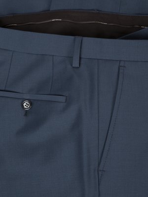 Detailaufnahme einer dunkelblauen Stoffhose. Die Hose hat eine Hosentasche mit einem Knopf, einen Schlitz mit einer weiteren Tasche sowie einen Gürtelschlaufenansatz. Im oberen Bereich ist ein Teil des Hosenbundes zu sehen.