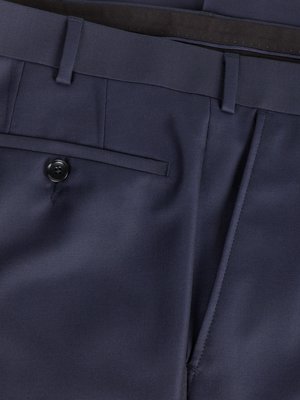 Nahaufnahme einer dunkelblauen Stoffhose. Sichtbar sind eine Hosentasche mit Knopf, eine Seitentasche und der Hosenbund mit Schlaufen. Der Gürtel ist nur teilweise zu sehen.