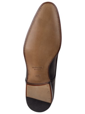 Draufsicht auf die Sohle eines schwarzen Lederschuhs. Der Schuh hat eine braune Ledersohle mit der Aufschrift "Magnanni", Schuhgröße 41 1/2 ist sichtbar. Der Absatz ist schwarz.