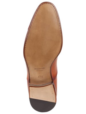 Die Unterseite eines braunen Lederschuhs. Die Schuhsohle ist hellbraun, die Ferse dunkelbraun. Auf der Sohle ist "MAGNANNI" und die Größe "41 1/2" zu sehen. Der Rand ist mit einem braunen Faden genäht.