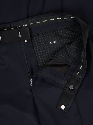 Draufsicht auf eine blaue Hose. Der Hosenbund mit Aufschrift "BOSS" ist deutlich zu sehen. Der Reißverschluss ist geöffnet. Innenfutter mit Muster aus BOSS-Schriftzügen, darunter ein Schild mit BOSS-Schriftzug.