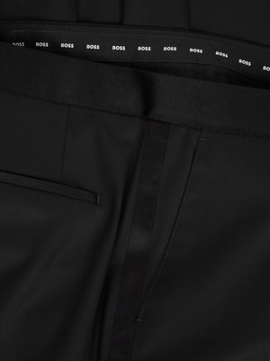 Nahaufnahme einer schwarzen Hose. Oben ist ein Bund mit dem Schriftzug "BOSS" in regelmäßigen Abständen zu sehen. Der Stoff hat eine glatte Oberfläche, eine seitliche Naht ist angedeutet. Auf der linken Seite ist eine kleine Tasche zu sehen.