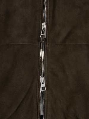 Nahaufnahme eines Reißverschlusses an einer braunen Jacke. Der Reißverschluss ist metallisch und mit zwei Reißverschluss-Anhängern versehen. Die Jacke hat eine leicht strukturierte Oberfläche.