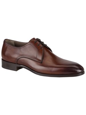 Ein brauner Lederschuh für Herren, seitlich betrachtet. Der Schuh hat Schnürsenkel und eine glatte Oberfläche mit leichter Farbverlauf. Er steht auf einer dunklen Sohle.