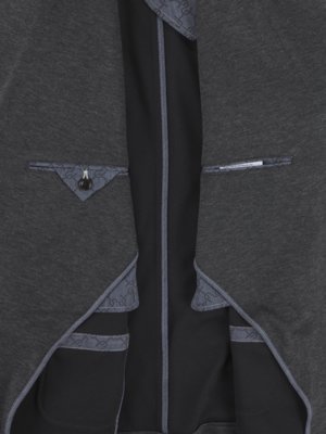 Nahaufnahme der Innenseite eines grauen Sakkos. Schwarzes Futter mit grauem Zierband. Auf der linken Seite eine kleine dreieckige Tasche mit Knopf. Auf der rechten Seite eine horizontale Tasche.