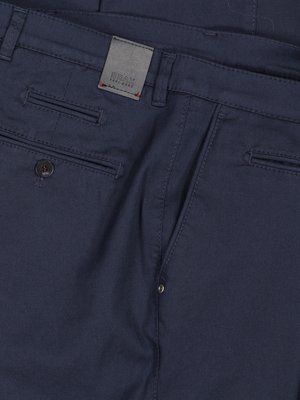 Nahaufnahme einer dunkelblauen Hose mit Seitentaschen, einer Gesäßtasche und einer kleinen Lederlasche mit dem Markenlogo "GRAY". Der Knopf der Tasche ist sichtbar.