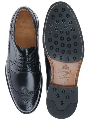 Zwei schwarze Herrenschuhe, einer mit der Sohle nach oben und der andere von oben betrachtet. Der Schuh mit der Sohle nach oben hat eine schwarze Profilsohle. Der andere Schuh hat eine glatte Oberfläche und Lochmuster. Auf beiden Schuhen ist "Berwick 1707" aufgedruckt.