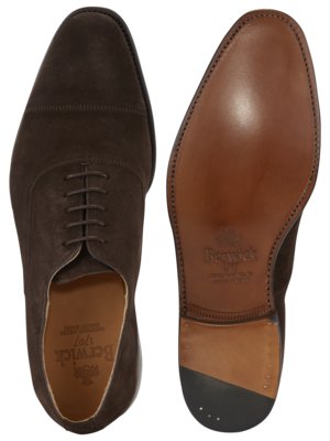 Ein Paar braune Wildleder-Schnürschuhe, von oben und die Sohle von unten fotografiert. Der Schuh oben hat Schnürsenkel. Die Sohle des zweiten Schuhs ist braun und trägt das Logo "Berwick 1707".
