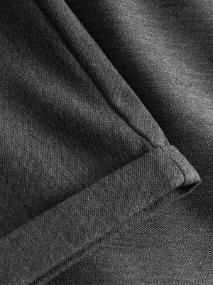 Nahaufnahme einer dunkelgrauen Stofffalte, die durch das Aufrollen des Stoffes entstanden ist. Der Stoff hat eine sichtbare Textur, die durch die Webart entsteht. Die gerollte Kante ist sichtbar.