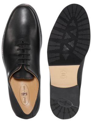 Zwei schwarze Lederschuhe auf weißem Hintergrund. Ein Schuh ist von oben mit Schnürsenkeln zu sehen, der andere von unten mit profilierter Sohle und Ledereinlage. Auf der Sohle befinden sich Markennamen.
