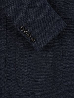 Nahaufnahme eines dunkelblauen Sakkos. Man sieht Ärmel, Knöpfe und eine aufgesetzte Tasche. Auf dem Ärmel sind vier schwarze Knöpfe aufgereiht. Der Stoff hat eine feine Struktur.