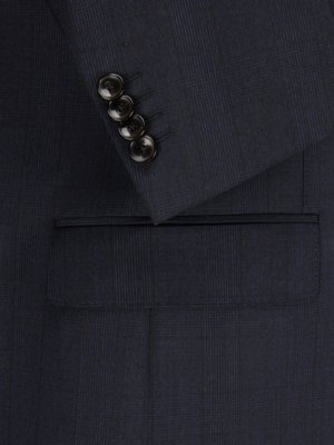 Nahaufnahme einer dunkelblauen Jacke. Vier schwarze Knöpfe sind auf dem Ärmel zu sehen. Darunter befindet sich eine quadratische Tasche. Der Stoff ist mit einem feinen Muster versehen.