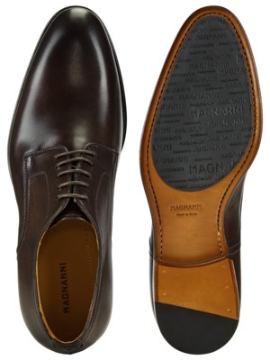 Zwei braune Lederschuhe, jeweils von oben und von unten abgebildet. Der linke Schuh ist ein Schnürschuh. Auf der Sohle des rechten Schuhs steht "MAGNANNI" mehrfach.
