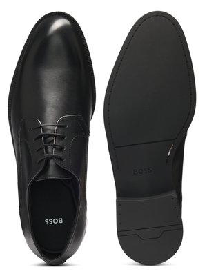 Ein Bild zeigt einen schwarzen Herrenschuh und dessen Sohle nebeneinander. Der Schuh hat Schnürsenkel und die Wortmarke BOSS innen. Die Schuhsohle ist ebenfalls schwarz, mit der Aufschrift BOSS und Profil.