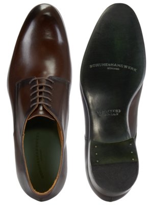 Ein brauner Lederschuh von oben gesehen, daneben die Schuhsohle. Auf dem Schuh steht "Schuhe&Handwerk". Auf der Sohle steht "VERO CUOIO, MADE IN ITALY" und "Schuhe&Handwerk".