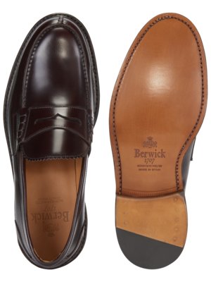 Ansicht von oben auf einen braunen Penny Loafer-Schuh. Links der Schuh, rechts die Sohle, die den Markenamen "Berwick" zeigt. Die Schuhe haben eine glänzende Oberfläche. Die Sohle zeigt eine helle Farbe mit Nähten.
