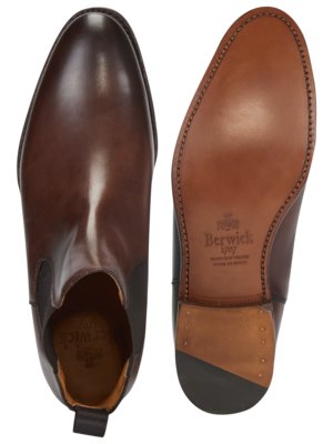 Zwei braune Chelsea-Stiefel, einer von oben gesehen, einer von unten. Der von oben gezeigte Stiefel hat einen glänzenden Schaft. Der untere Stiefel zeigt die Sohle mit dem Markennamen "Berwick 1707".