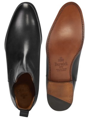 Zwei schwarze Chelsea-Stiefel, einer auf der linken Seite mit Oberseite nach oben, der andere auf der rechten Seite mit Sohle nach oben. Die braune Sohle trägt den Markennamen Berwick. Die schwarzen Schuhe sind aus Leder.