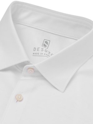 Nahaufnahme eines weißen Hemdkragens. Zwei Knöpfe sind im geöffneten Zustand zu sehen. Das Logo "DESOTO MADE IN EUR" ist sichtbar. Der Kragen ist weiss, ebenso der Stoff.