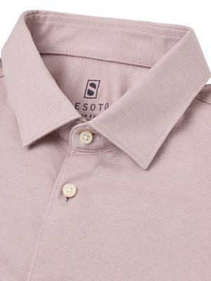 Nahaufnahme eines rosafarbenen Poloshirts mit Knöpfen. Der Kragen des Hemdes ist ausgebreitet. Auf dem Etikett steht "ESOTO" mit einem Logo. Die Knöpfe sind cremefarben.