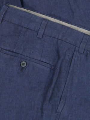 Nahaufnahme eines Teils einer blauen Leinenhose. Sichtbar sind eine Gesäßtasche mit Knopf, die Gürtelschlaufen, der Hosenbund mit Innenfutter und eine weitere Tasche. Die Hose ist mit Nähten versehen.