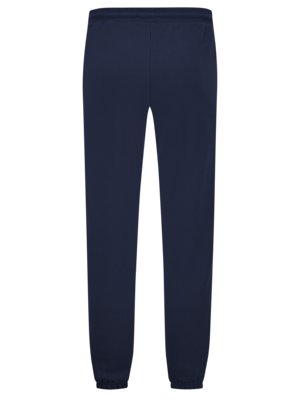 Dunkelblaue Sporthose. Die Hose hat einen Gummibund, der Stoff ist glatt und dehnbar, die Hosenbeine sind an den Knöcheln eng. Das Kleidungsstück ist mittig platziert und vor weißem Hintergrund.