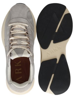 Ansicht von oben auf einen grauen Sneaker und seine Sohle. Der Sneaker hat helle Schnürsenkel und die Sohle ist cremefarben mit schwarzen Gummibereichen. Auf der Sohle steht "ARKK". Beide Teile sind auf weißem Hintergrund.