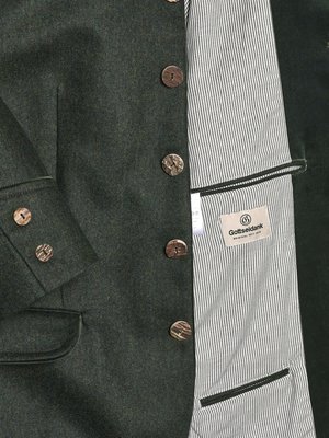 Dunkelgrüner Blazer aus Stoff mit sichtbaren Knöpfen aus Holz. Das Innenfutter des Blazers ist mit weißen Streifen versehen. Auf dem Innenfutter befindet sich ein Etikett mit dem Schriftzug "Gottseidank".