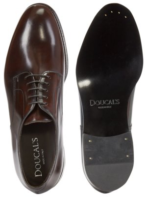 Draufsicht auf einen braunen Lederschuh und die Schuhsohle. Der linke Schuh ist geschnürt, zeigt die Marke "Doucal's" im Schuhinneren. Die Sohle hat die Marke "Doucal's" eingeprägt, mit Details der Sohlenkonstruktion, wie Metallstiften.