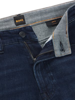 Nahaufnahme einer dunklen Jeans. Der Reißverschluss ist geöffnet. Auf dem Bundetikett steht BOSS. Rechts oben ist ein Etikett mit Onyx Slim Fit zu sehen.