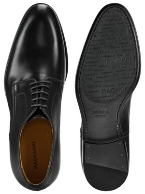 Ein Paar schwarze Lederschuhe mit Schnürsenkeln. Der linke Schuh ist von oben zu sehen, der rechte von unten, mit der Sohle und dem eingeprägten Markenlogo MAGNANNI. Die Schuhe haben eine glatte Oberfläche.