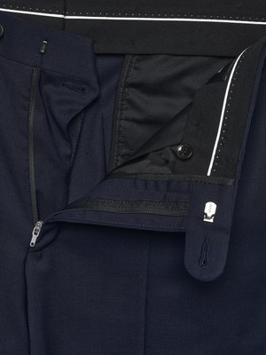 Nahaufnahme einer geöffneten, dunkelblauen Hose. Die Hose hat einen Reißverschluss, einen Knopf, einen Haken und eine Öse. Das Innenfutter der Hose ist schwarz. Oberhalb des Hosenbundes ist ein weißer Streifen mit kleinen schwarzen Punkten zu sehen.