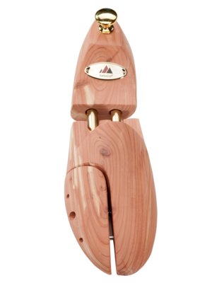 Ein Schuhspanner aus hellem Holz mit goldfarbenen Details, auf weißem Hintergrund. Der Spanner ist in drei Teile unterteilt, mit einem goldfarbenen Knauf oben und einem Metallstück im unteren Bereich. Ein goldenes Schild mit Logo ist sichtbar.