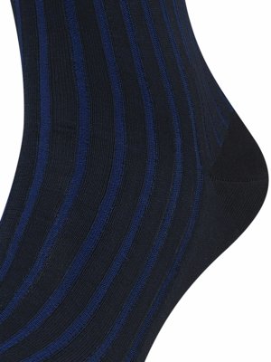 Nahaufnahme einer dunklen Socke mit vertikalen, gerippten Streifen in Marineblau auf schwarzem Hintergrund. Die Socke formt sich um den Fuß herum. Die Textur ist klar erkennbar.